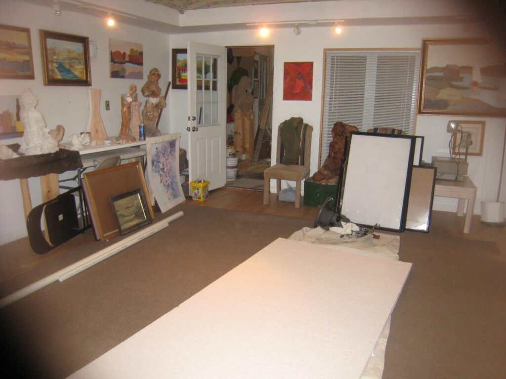 Studio interior with paintings and works arranged around an open floor