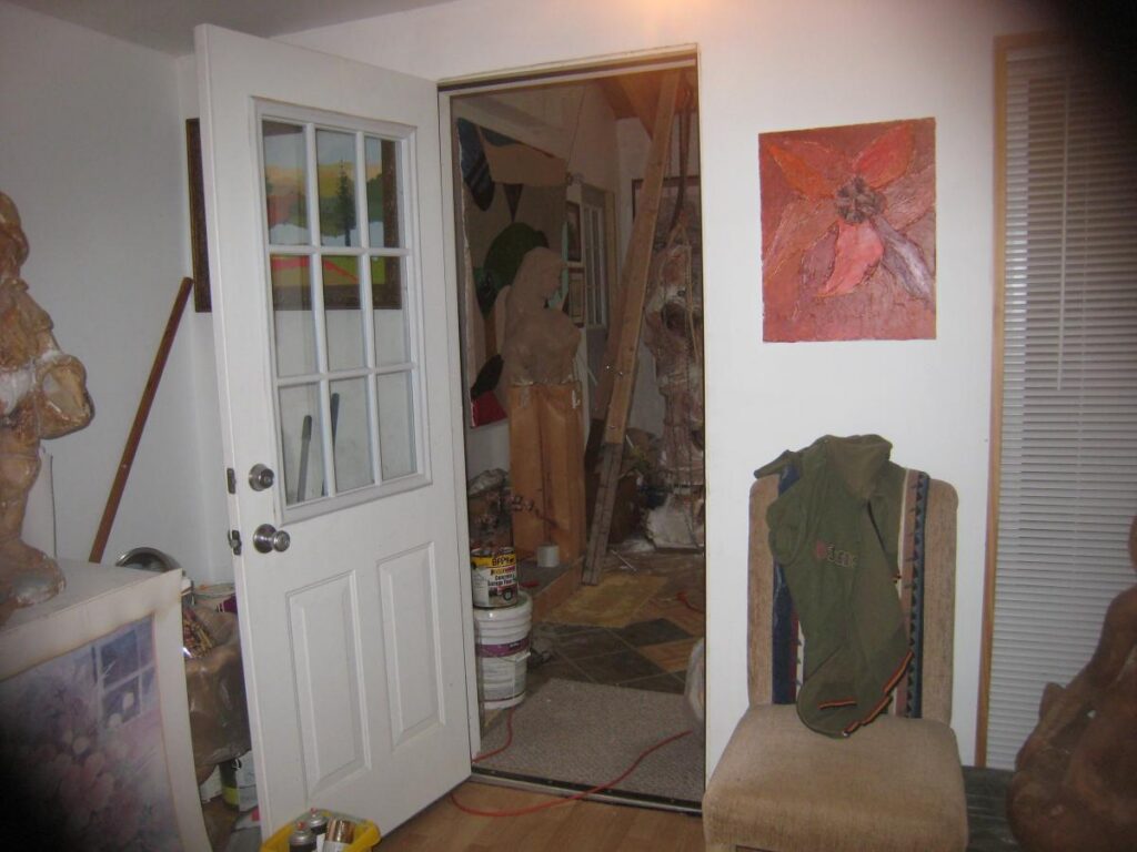 Sculptures and artwork visible through a white studio doorway