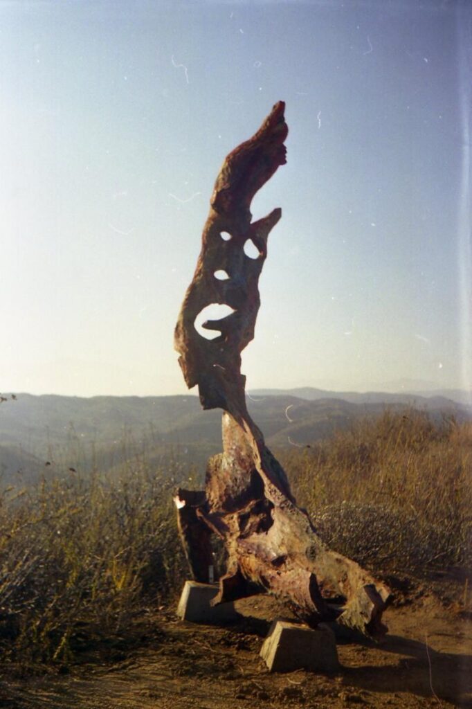 Dark upright outdoor sculpture against a blue sky