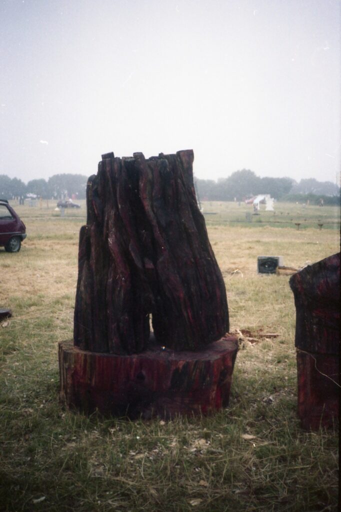 Group of dark carved sculptures arranged in an open field