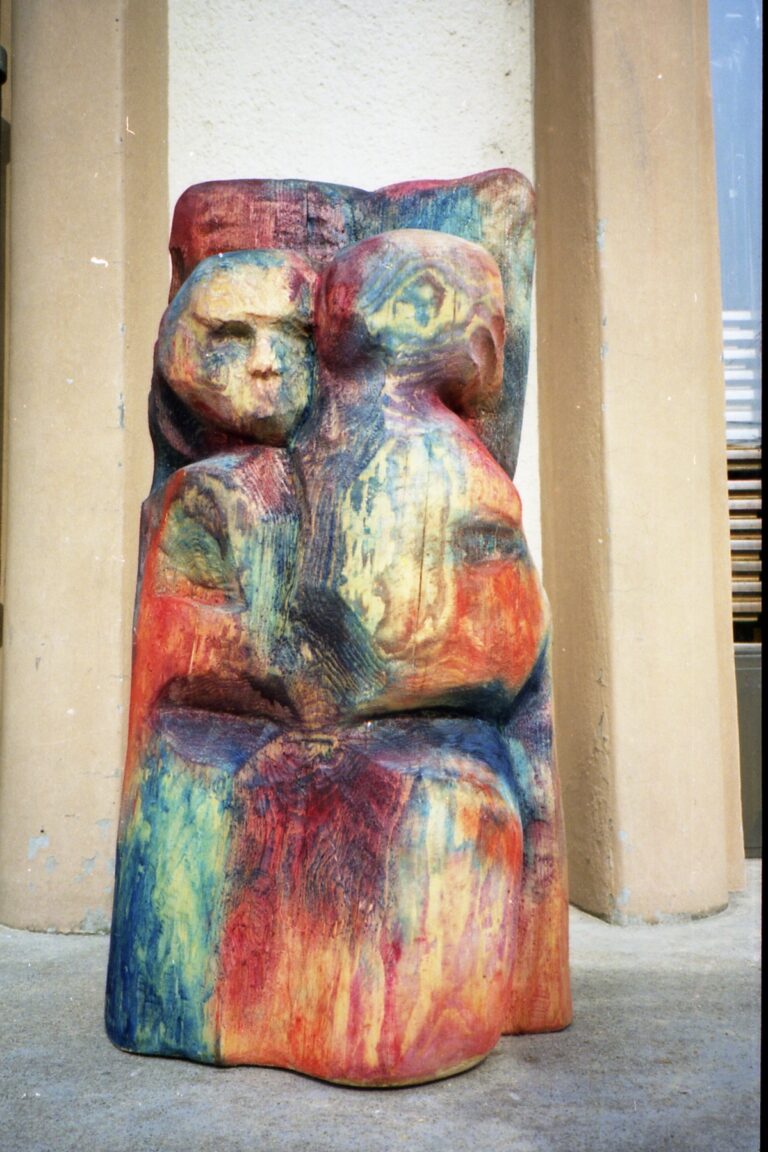 Two colorful carved totem-like sculptures beside a building