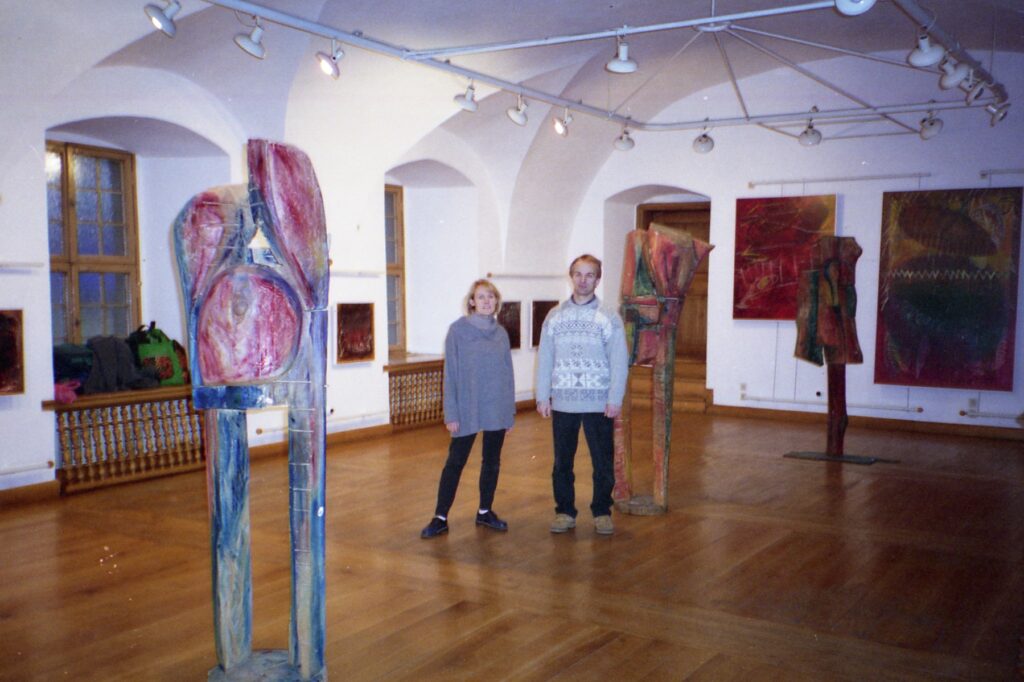 Archival gallery installation with sculpture, paintings, and two visitors