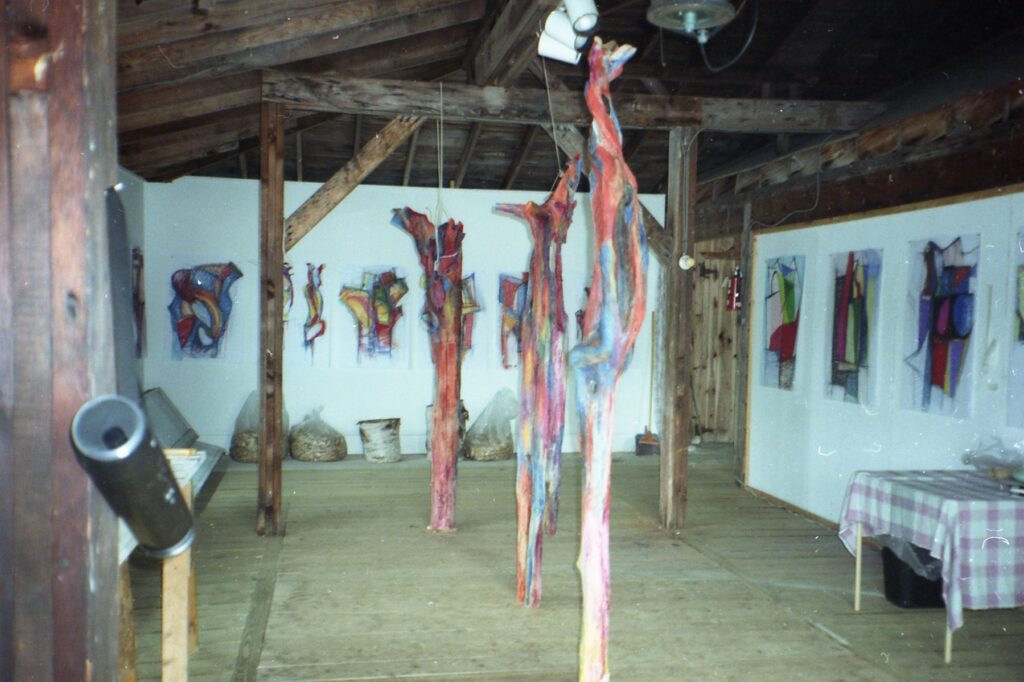 Archival installation view with tall painted sculptures and wall-mounted works
