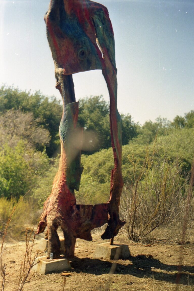 Tall outdoor sculpture with a framed opening above animal-like carved forms