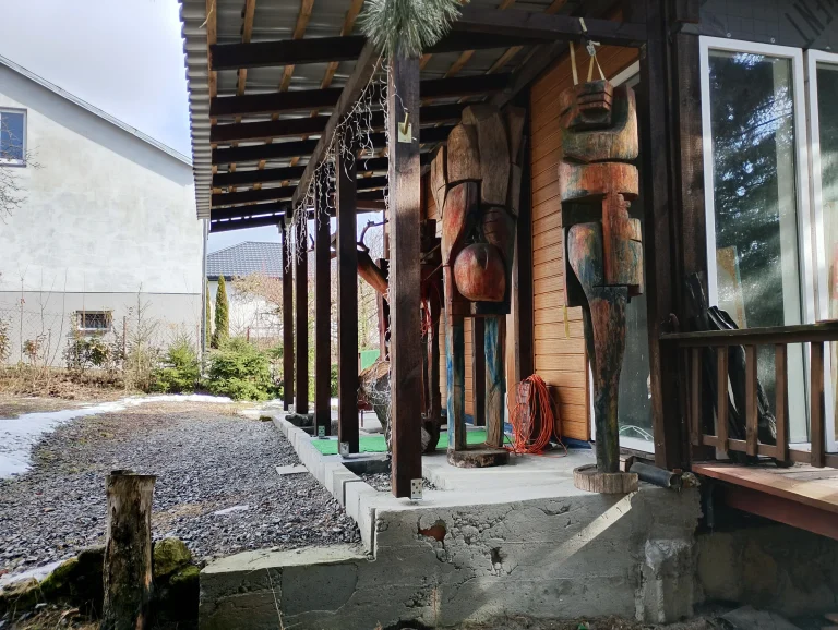Painted carved wooden sculptures displayed along a studio porch