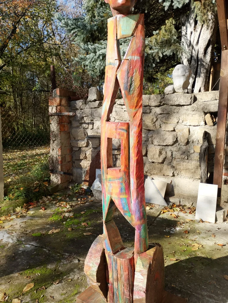 Tall colorful carved wooden figure standing outdoors