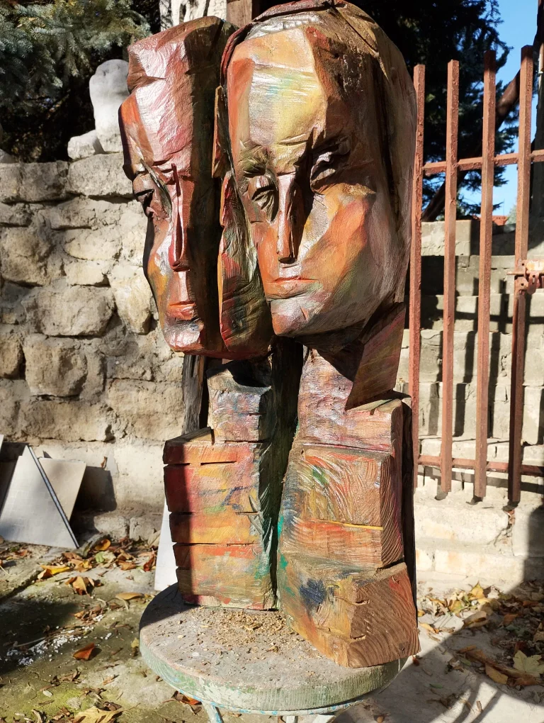Close view of a colorful carved wooden figure with an abstract face