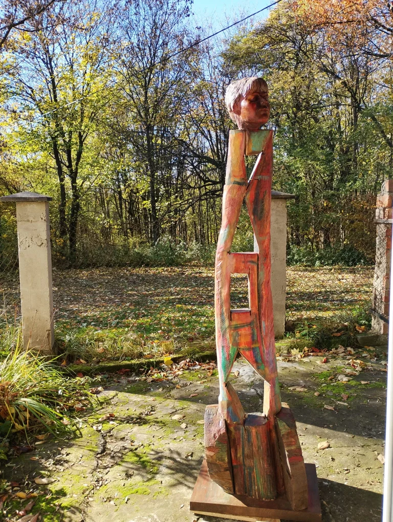 Tall painted wooden figure standing among autumn trees