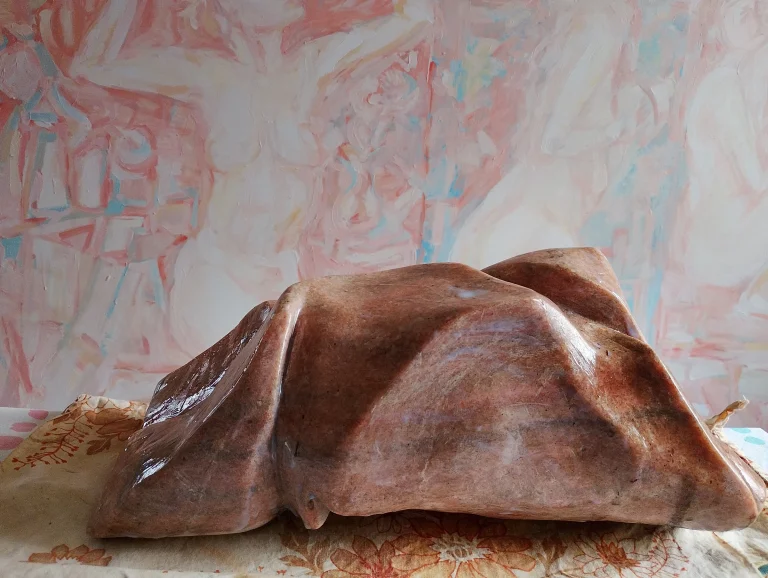 Low polished reddish-brown abstract stone sculpture with flowing folded forms