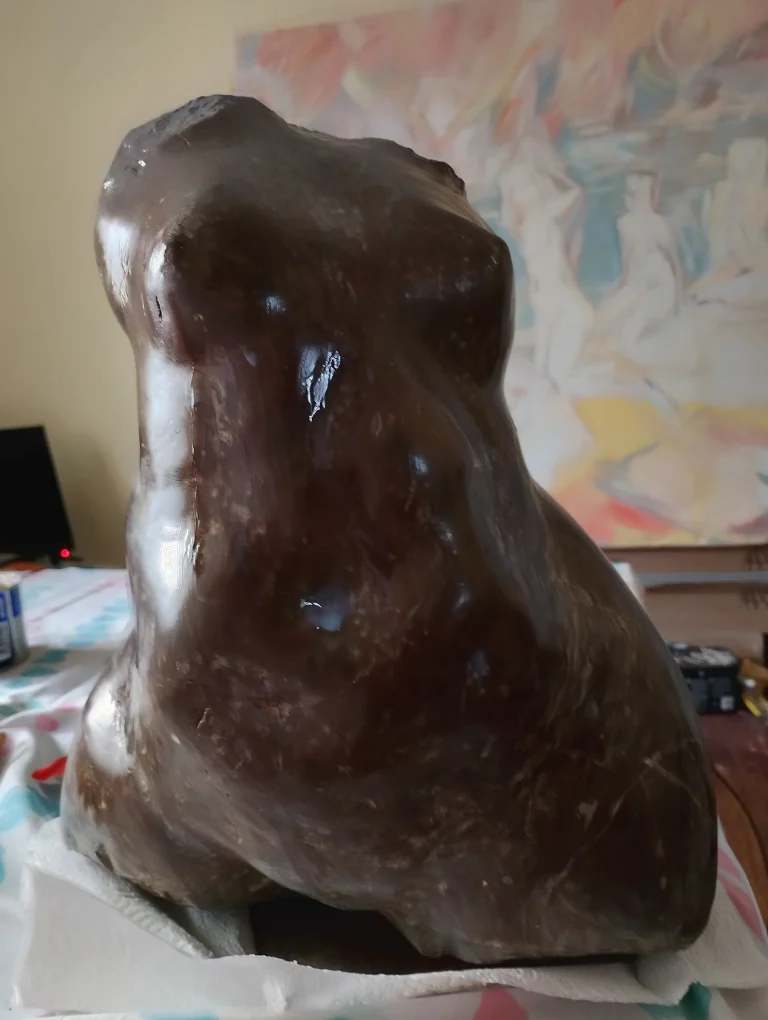 Three-quarter view of a polished dark brown abstract stone sculpture